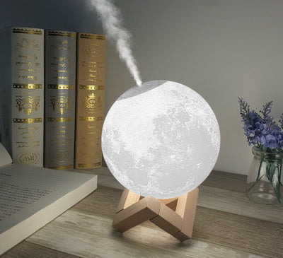 Moon-shaped humidifier and night light with a white deer stand, emitting mist, on a wooden table with books. - Image 3
