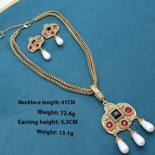 Vintage gold-toned necklace with double chain, ornate pendant featuring red and black glass inlays, and three white pearl tassels. - Image 9