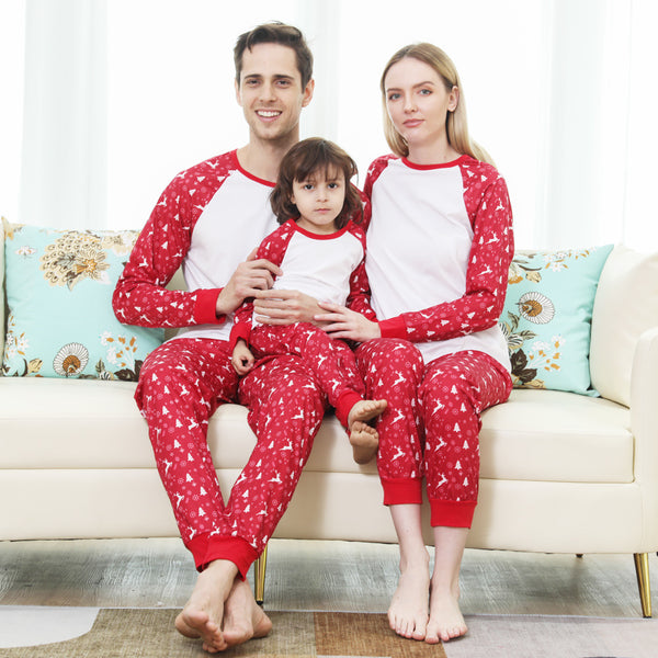 Family matching Christmas pajamas: black long-sleeve tops with white deer prints and red buffalo plaid pants.