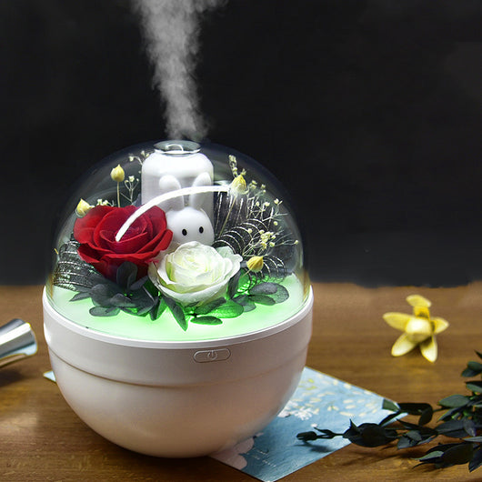 White spherical aroma diffuser with clear dome, featuring preserved blue roses, blue hydrangea, and a white rabbit figurine.