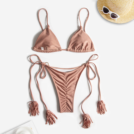 Black string bikini with wrap-around straps and gold-tone rings with tassels modeled on a beach. - Image 12