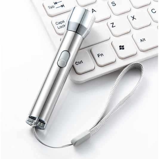 Silver stainless steel laser pointer pet toy with a grey wrist strap, resting on a white computer keyboard.
