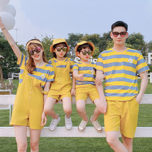 Family of four wearing matching yellow and blue striped t-shirts with daisy appliques. Mother and daughter wear yellow short overalls, father and son wear yello - Image 8