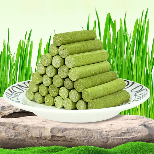 Clear plastic container of green freeze-dried cat grass chicken stick treats with a label featuring a grey cat.