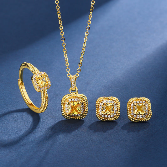 Women's gold-toned jewelry set with a ring, necklace, and stud earrings, each featuring a square yellow gemstone surrounded by small clear stones.