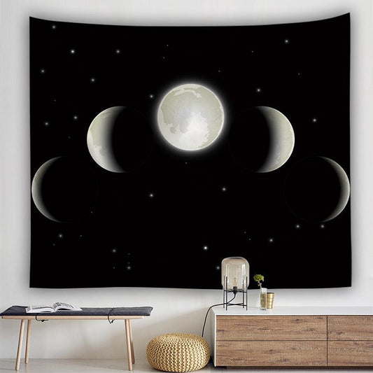 Black tapestry with a white moon cycle design and small stars, hanging above a modern wooden bench and cabinet.