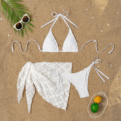 White lace halter bikini set with a matching mesh sarong, laid out on sand with sunglasses and a palm leaf. - Image 22