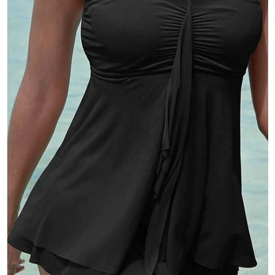 Woman in a brown strapless ruched one-piece swimdress with a flowing skirt, standing in shallow ocean water. - Image 4
