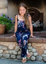 Woman wearing a navy blue floral wide-leg jumpsuit with pink and white flowers, tie-shoulder straps, and a drawstring waist. - Image 6