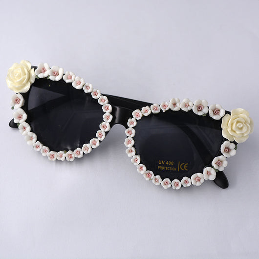 Black cat-eye sunglasses with dark lenses, adorned with small red rose embellishments along the frames. - Image 3