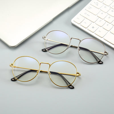 Gold round-frame anti-blue light glasses with clear resin lenses on a gray textured surface next to a notebook. - Image 5