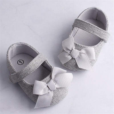 Grey herringbone baby crib shoes with white grosgrain bows and a single strap, perfect for toddlers.