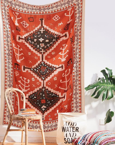 Red tapestry with black and white geometric tribal pattern hanging on a white wall above decorative pillows. - Image 7