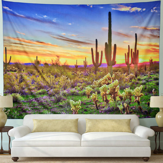 Printed tapestry featuring a vibrant desert sunset with saguaro and cholla cacti, displayed above a white sofa.