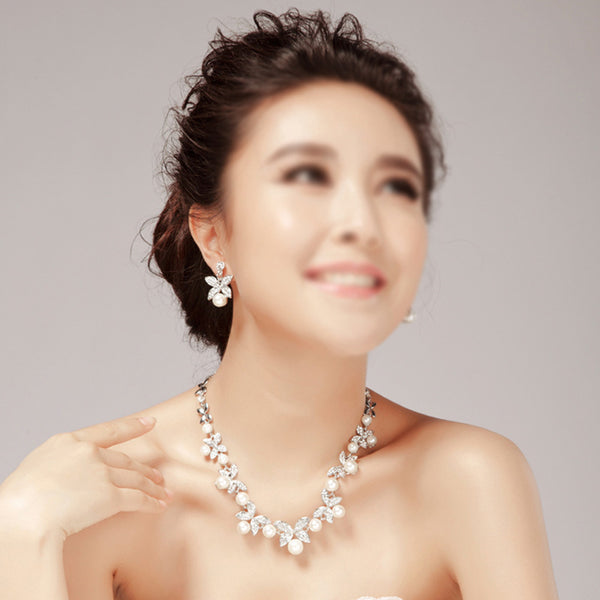 Elegant bridal jewelry set featuring a pearl and rhinestone floral necklace with matching drop earrings on a model. - Image 3