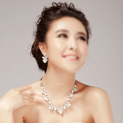 Elegant bridal jewelry set featuring a pearl and rhinestone floral necklace with matching drop earrings on a model. - Image 3