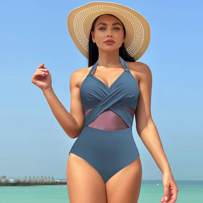 Woman in a green halter-neck one-piece swimsuit with cross-strap design and mesh cutouts, on a beach. - Image 29