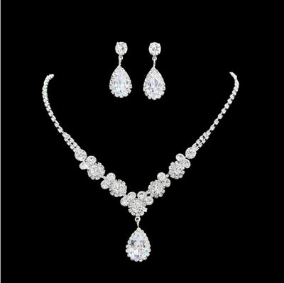 Sparkling silver-toned necklace and matching teardrop earrings set with clear stones, displayed on a black stand. - Image 6