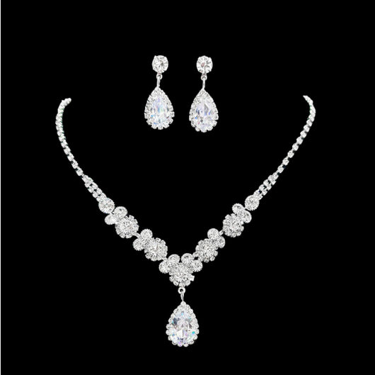 Sparkling silver-toned necklace and matching teardrop earrings set with clear stones, displayed on a black stand. - Image 6