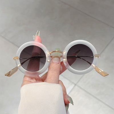 Small frame oval fashion sunglasses with black frames and vibrant orange lenses, held by a hand. - Image 4