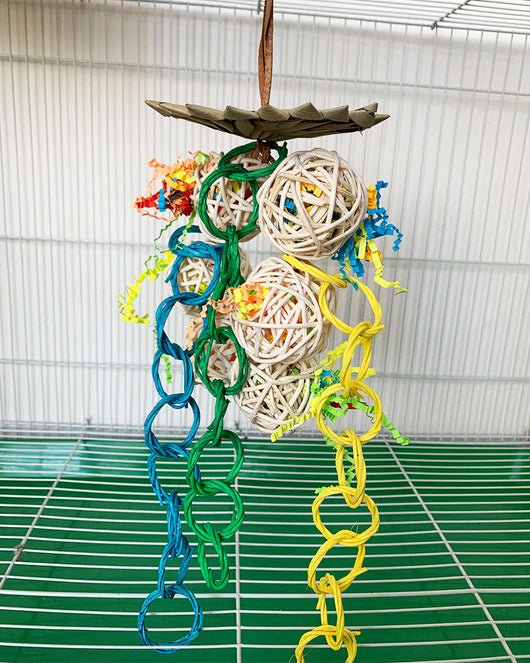 Colorful parrot chew toy made from natural fibers, featuring a woven ball, leaf-like accents, a bell, and a carabiner clip. - Image 7