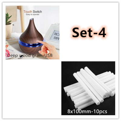 Dark wood grain LED essential oil diffuser with a blue light band and touch switch, shown with a hand operating it. Includes a bundle of 10 white filter sticks. - Image 11