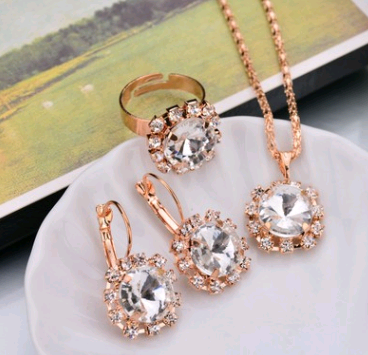 Rose gold-toned necklace, earrings, and ring set with large oval clear gemstones surrounded by smaller stones. - Image 25