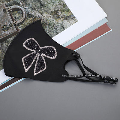 Black ear-mounted mask with a sparkling rhinestone bow pattern, featuring adjustable ear loops. - Image 15