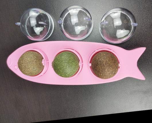 Pink fish-shaped cat molar stick toy with three compartments holding green and brown catnip or silvervine balls. Three clear plastic dome covers are shown. - Image 6