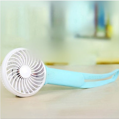 Lime green and white mini USB portable fan with a flexible strap, lying on a light wooden surface. - Image 5