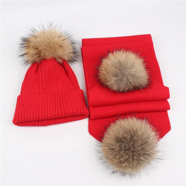 Red knitted hat and scarf set with fluffy brown and black fur pom-poms, ideal for warm winter wear.