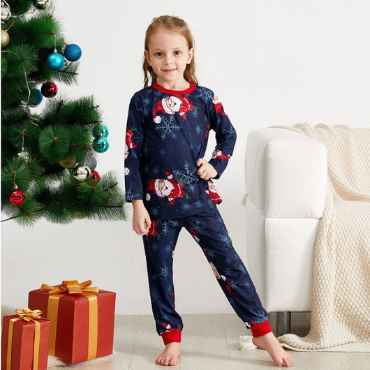 Family of four wearing matching navy blue Christmas pajamas with Santa Claus and snowflake print, red trim. - Image 4