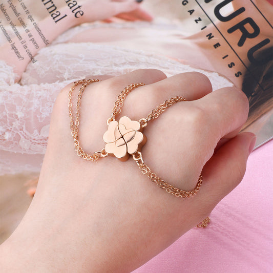 Four silver-colored necklaces, each with a half-heart charm that forms a four-leaf clover when combined, on pink satin.