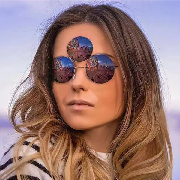 Red lens round sunglasses with a gold metal frame and an extra small round lens above the left eye.