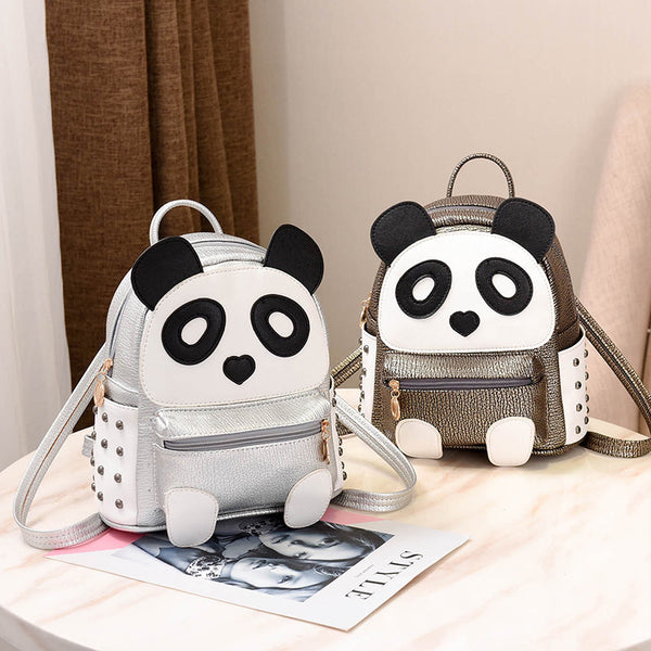 Metallic gold and white cartoon panda backpack with black ears and eye patches, a heart nose, and studded side panels.