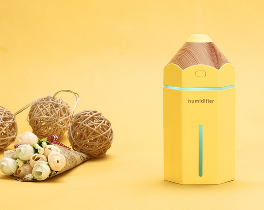 Light blue pencil-shaped mini humidifier with wood-grain top and glowing green light, next to a white teacup and pink gift box. - Image 6