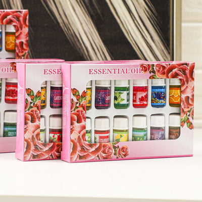 A 12-piece essential oil set in a decorative pink box with a rose floral design. Includes scents like Lavender, Rose, Lemon, and Green Tea.