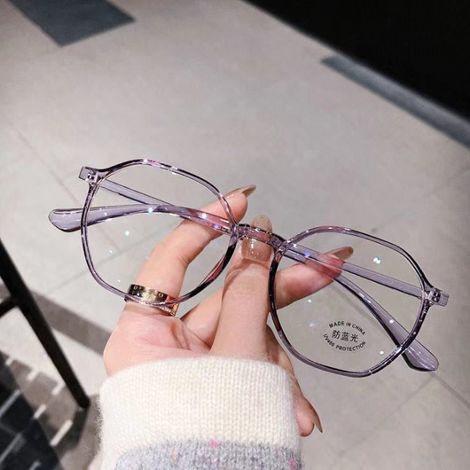 Transparent blue anti-blue light glasses with a vintage round frame and clear lenses, held by a hand. - Image 2