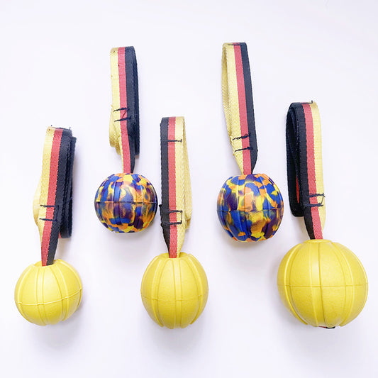 Yellow EVA pet training ball with a black, red, and yellow striped tether, designed for water play.