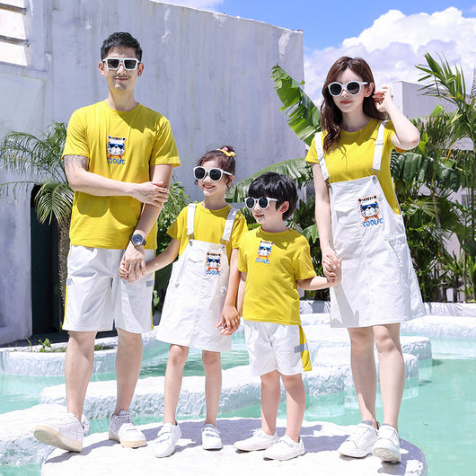 Family of three in matching yellow t-shirts and white outfits by a pool. Father and son wear shorts, mother and daughter wear overall dresses. - Image 4
