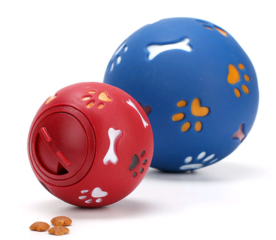 Red rubber pet puzzle ball with white, blue, and orange paw print and bone cutouts, featuring a treat dispenser opening. - Image 3