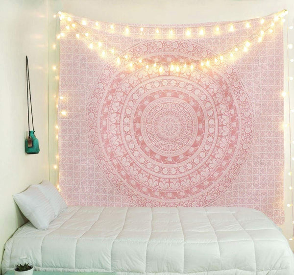 Gold and blue mandala tapestry with elephant and floral patterns, hung above a white quilted bed.