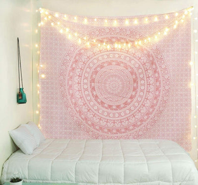Gold and blue mandala tapestry with elephant and floral patterns, hung above a white quilted bed.