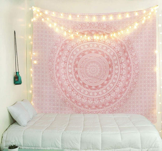Gold and blue mandala tapestry with elephant and floral patterns, hung above a white quilted bed.