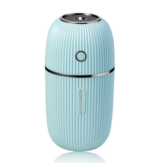 Pink mini ultrasonic air humidifier with ribbed texture and rose gold accents, emitting a fine mist on a white shelf.