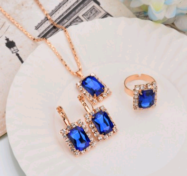 Rose gold-toned necklace, earrings, and ring set with large oval clear gemstones surrounded by smaller stones. - Image 9