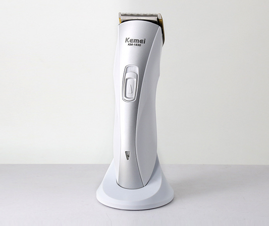 White and silver Kemei KM-1830 electric hair clipper with a charging base on a light background.