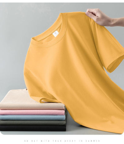 Light gray short-sleeve t-shirt with a round neck, held up to show its smooth fabric. A stack of folded t-shirts in various colors is visible in the background. - Image 21