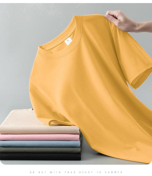 Light gray short-sleeve t-shirt with a round neck, held up to show its smooth fabric. A stack of folded t-shirts in various colors is visible in the background. - Image 21