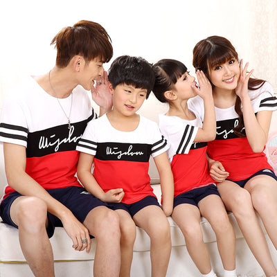 Family of four wearing matching black, white, and red color block t-shirts with navy shorts, posing happily. - Image 6